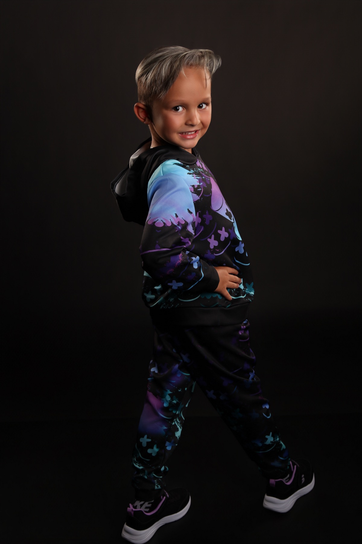 Christopher posing in a neon graphic hoodie on a dark studio background
