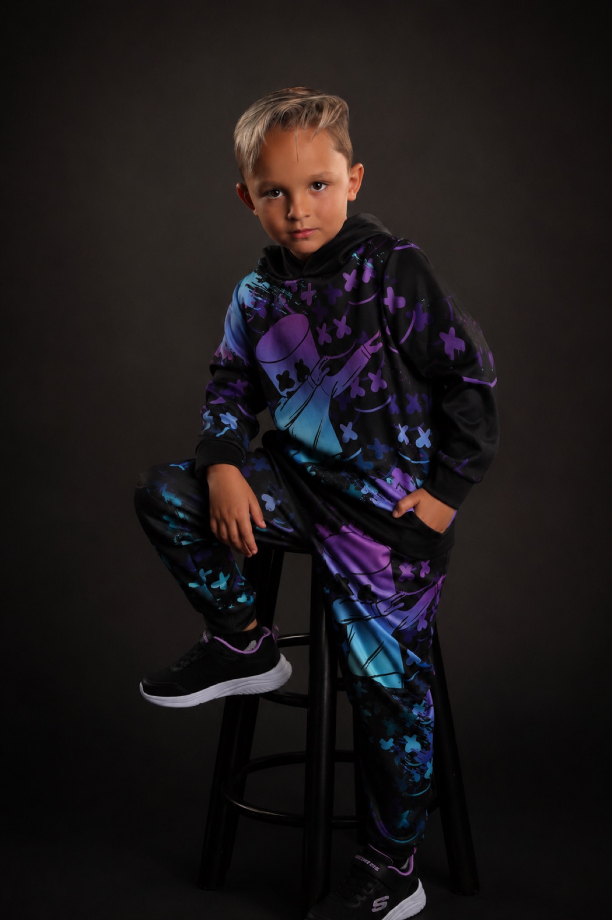 Neon look — purple graphic tracksuit, seated on a stool